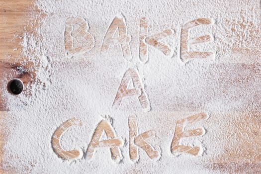 Bake a cake written in flour on a wooden surface