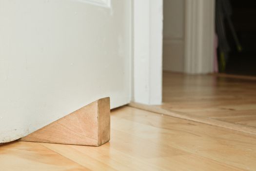 A wooden door stopper on a laminate floor