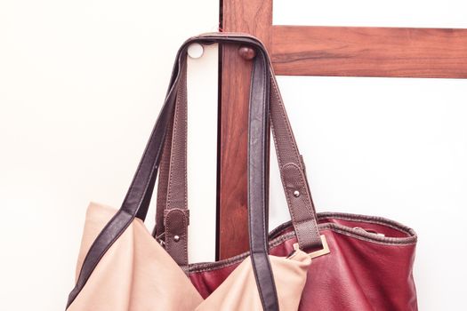 Two leather ladies' handbags hanging on a wardrobe door