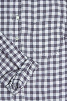 Front of a gingham shirt with a rolled up sleeve