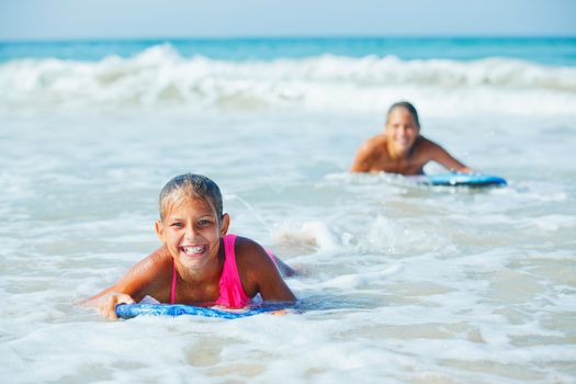 Summer vacation - Happy cute girl having fun with surfboard in the ocean