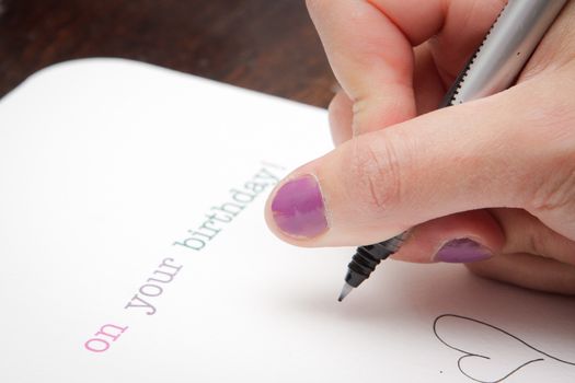 Close up of a woman's hand writing a birthday card