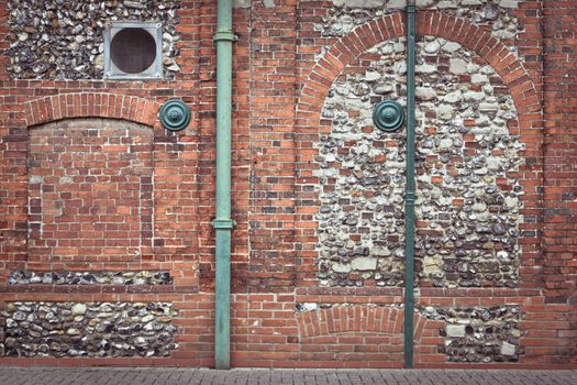 Green pipes against a red brick wall