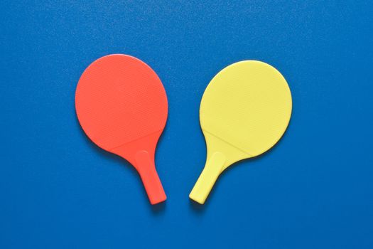 Two toy tennis bats on a blue background