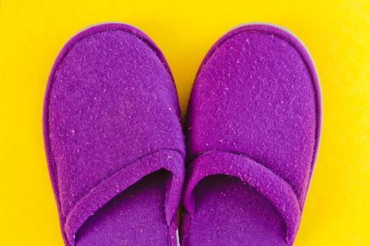 Pair of soft purple slippers on a yellow background