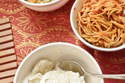 Close up of potato salad and noodles in bowls on a table cloth