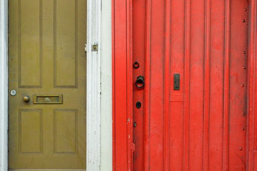 Ajacent green and red wooden front doors of English cottages