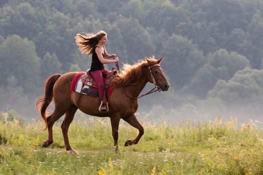 Young girl with long hair riding galloping horse breed Quarter