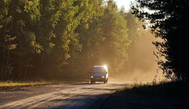 Car on the Road through forest in sunset fog. 