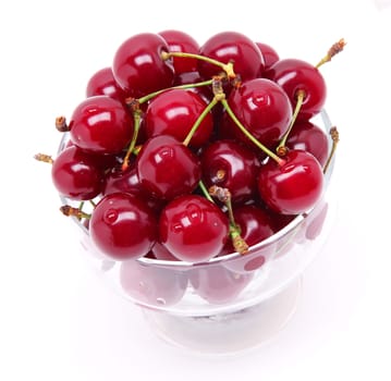 Ripe fresh cherry in the chrystal glass isolated on white background