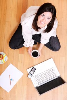 A young adult woman studying on the floor.