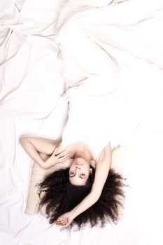 A young latin woman lying down in bed.