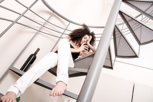 A young brazilian woman sitting on the stairs with a glass of red wine.