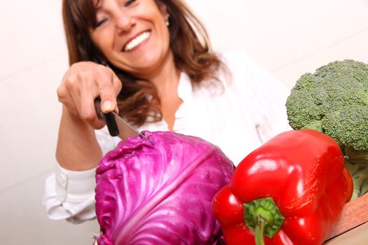 A beautiful mature woman cutting vegetables in the kitchen.