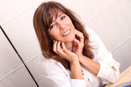 Portrait of a beautiful mature woman sitting in the kitchen.