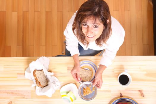 Portrait of a beautiful mature woman sitting in the kitchen. Focus on the Table.