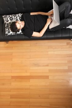 A young hispanic man with a laptop on the Sofa.