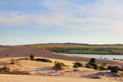 Sand desert and lake landscape under bluy sky at sunny day