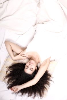 A young latin woman lying down in bed.