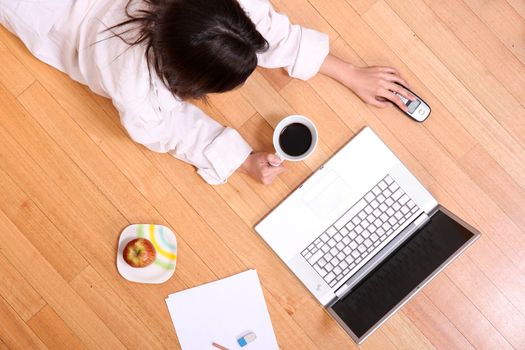 A young adult woman studying on the floor.
