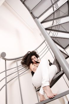 A young brazilian woman sitting on the stairs with a glass of red wine.