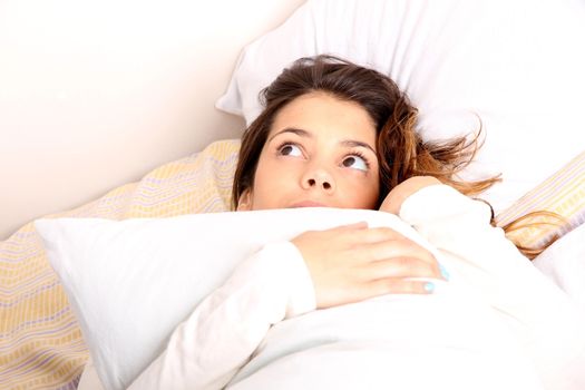 A daydreaming woman holding a pillow.