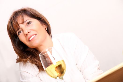 A beautiful mature woman with a glass of white wine.