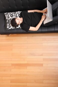 A young hispanic man with a laptop on the Sofa.