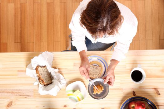 Portrait of a beautiful mature woman sitting in the kitchen. Focus on the Table.