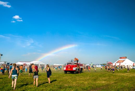 People enjoy the water from a fire truck on rainbow background at Mighty Sounds festival 19th of July, 2013