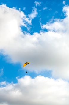 Flying paraglider on blue cloudy sky background