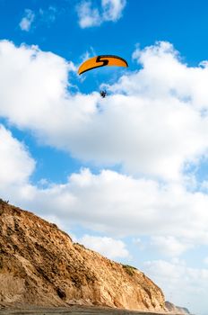 Flying paraglider on blue cloudy sky background