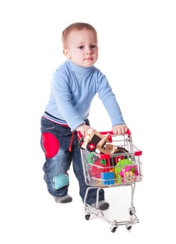 Boy plays with shopping trolley and toys, isolated on white