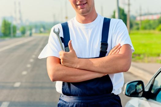 mechanic standing beside the car with a wrench