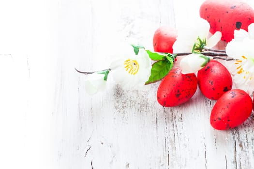 Red spotted eggs with apple flowers on the shabby wooden table