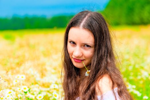Portrait of a young beautiful girl in camomile field