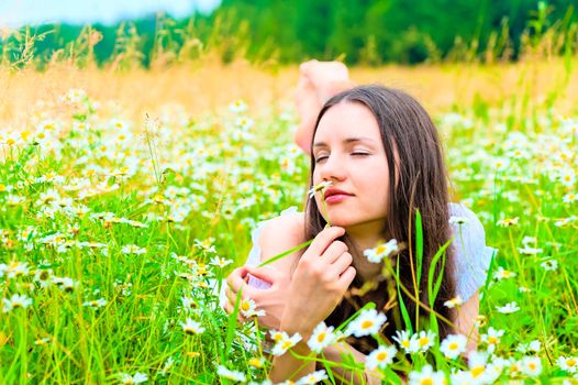 woman lying in a field and smelling a daisy