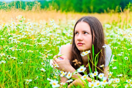 beautiful woman lies in a green field with flowers