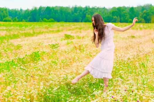 young ballerina dancing in a field with daisies