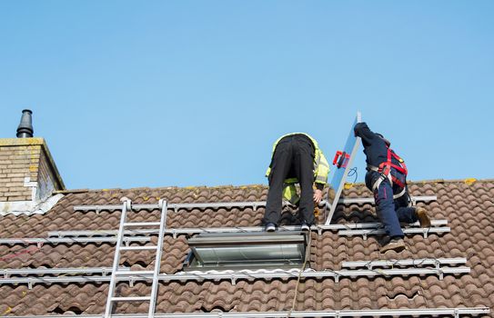 man putting the solar panel to the metal construction on the roof