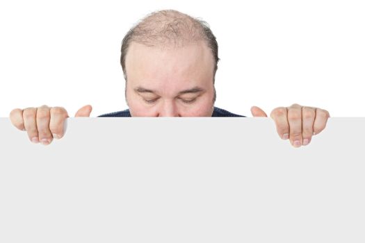 Businessman holding a blank white sign suitable for advertising looking down with closed eyes and hiding his face behind the board in an effort not to have to issue an endorsement
