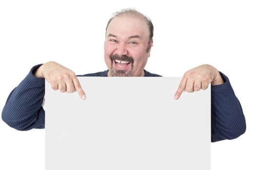 Enthusiastic middle-aged man with a goatee laughing and pointing to a blank white sign he is holding ing front of hiself with copyspace suitable for advertising or an announcement