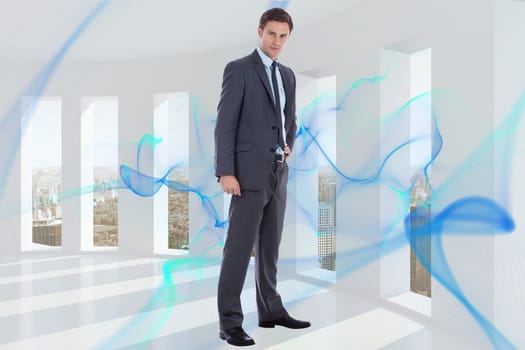 Serious businessman with hand on hip against blue abstract design in room