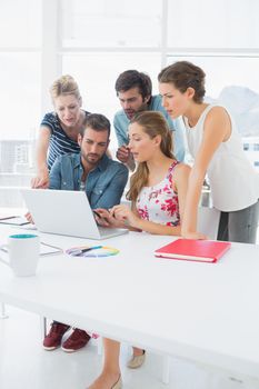 Young casual business people using laptop together in a bright office