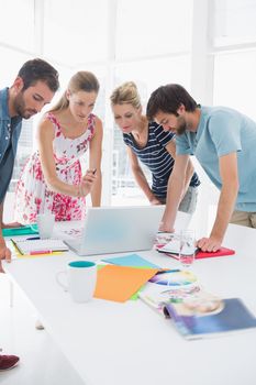 Young casual business people using laptop together in a bright office