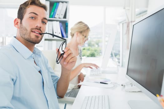 Side view of smiling casual young couple working on computer in a bright office