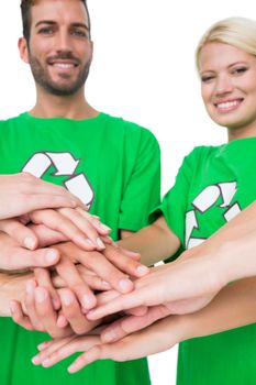 Portrait of young people in recycling symbol tshirts with hands together over white background