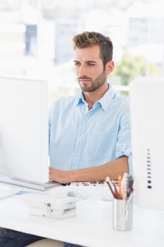 Concentrated young man using computer in a bright office