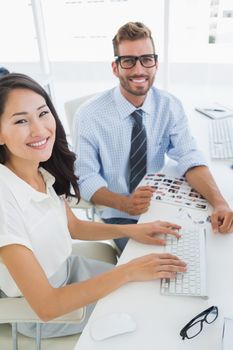 Side view of casual photo editors working on computer in a bright office