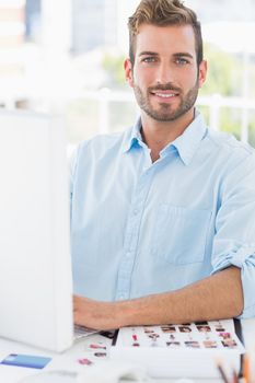 Portrait of a smiling young man using computer in a bright office